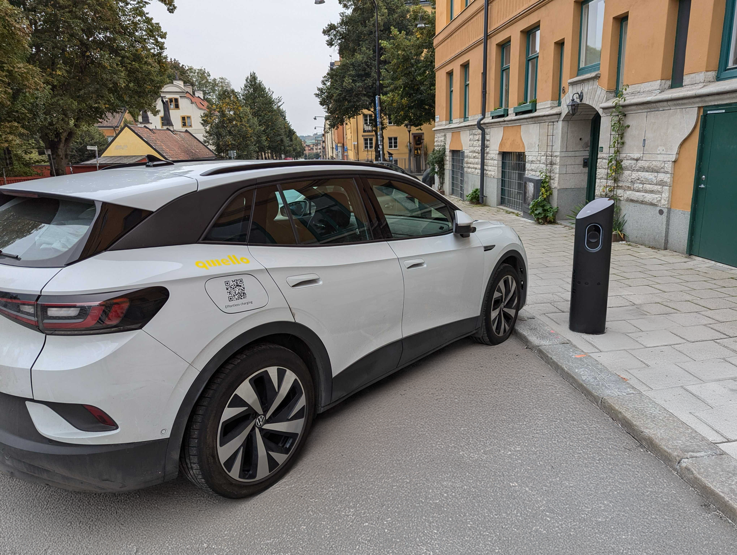 a car is parked at 30 degrees. At the sidewalk there is a charging pole.